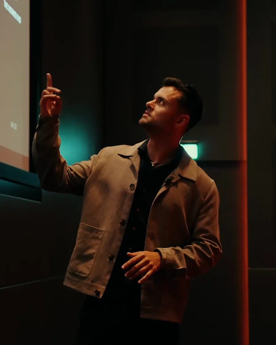 Ethan Monkhouse on stage, pointing to a slide